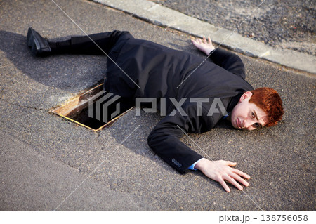 Portrait, accident and an unlucky business man on a street in the city after falling into a hole. Mistake, stuck or clumsy and a ginger corporate professional on the road in a suit with a problem Portrait, accident and an unlucky business man on a street in the city after falling into a hole. Mistake, stuck or clumsy and a ginger corporate professional on the road in a suit with a problem 138756058