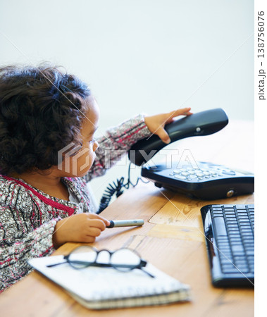 Playing, child and a telephone for a phone call at a desk for communication, pretend work or childhood. Playful, table and a girl, kid or baby with a landline for conversation, contact or secretary Playing, child and a telephone for a phone call at a desk for communication, pretend work or childhood. Playful, table and a girl, kid or baby with a landline for conversation, contact or secretary 138756076