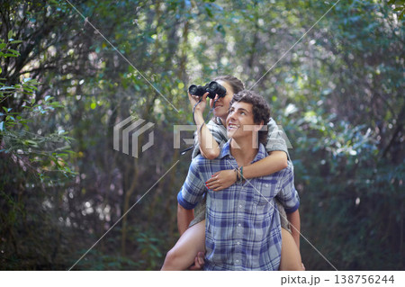 Man, woman and piggyback outdoor with binocular for travel, adventure or sightseeing in nature with happiness. Couple, people and tourist hiking in woods or forest for experience, holiday or vacation Man, woman and piggyback outdoor with binocular for travel, adventure or sightseeing in nature with happiness. Couple, people and tourist hiking in woods or forest for experience, holiday or vacation 138756244