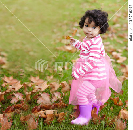 Portrait, child and playing in tutu on grass with brown leaves in autumn. Face, adorable kid and curly hair with rain boots outside for development, education and learning of seasons in environment Portrait, child and playing in tutu on grass with brown leaves in autumn. Face, adorable kid and curly hair with rain boots outside for development, education and learning of seasons in environment 138756298