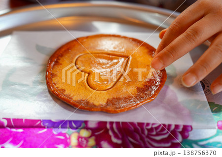 Child's Hands Carefully Carving Heart Shaped Dalgona Candy with a Toothpick in Korea 138756370
