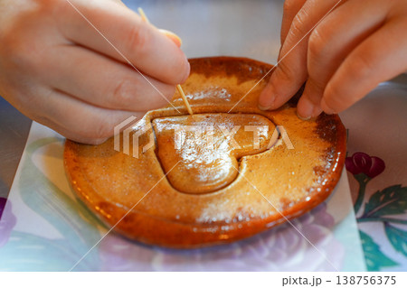 Child's Hands Carefully Carving Heart Shaped Dalgona Candy with a Toothpick in Korea Child's Hands Carefully Carving Heart Shaped Dalgona Candy with a Toothpick in Korea 138756375