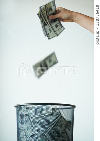 Bin, money or bills with finance, inflation or debt with bankruptcy, trash or global recession. Waste bucket, cash or economy issues with fraud, corruption or value decline on a studio background 138756419