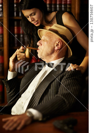 Woman, lighter and cigarette for man in mafia, boss or godfather with hat, suit and bowtie. Mature, person or businessman for criminal activity, power and danger in space with tobacco, puff and relax 138756607