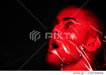 Man, red plastic and suffocate in studio isolated on a black background mockup. Polyethylene, film and person with depression, fear and anxiety, stress and mental health crisis, psychology and neon 138756608