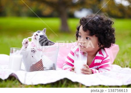 Milk, picnic and a girl in the park with her kitten together for love, care or bonding during summer. Summer, straw or kids and happy young child in the garden drinking from a glass with her pet cat 138756613
