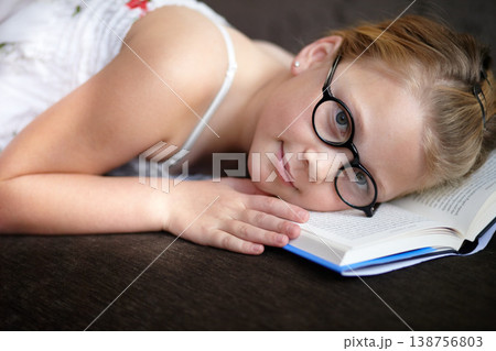 Portrait, education and a child reading a book for learning, studying or to relax on the floor. Library, young and a girl, kid or a student at school with a novel, story or getting ready for an exam Portrait, education and a child reading a book for learning, studying or to relax on the floor. Library, young and a girl, kid or a student at school with a novel, story or getting ready for an exam 138756803