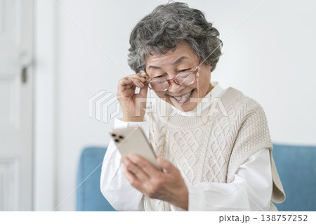 スマートフォンの画面を見る老眼鏡をかけたシニア女性 138757252