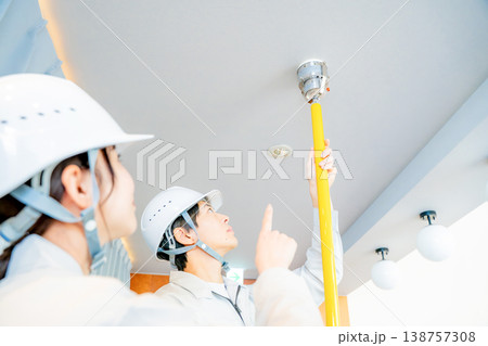 自動火災報知設備の点検をする作業着の男女 138757308