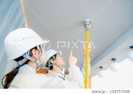 自動火災報知設備の点検をする作業着の男女 138757309
