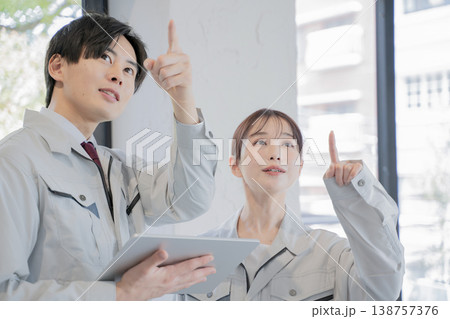 打ち合わせをする作業着の男性と女性 138757376
