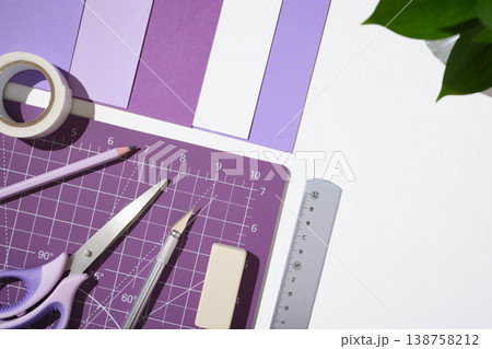 Creative workspace with purple hobby tools, paper, and cutting mat on white desk. Copyspace 138758212