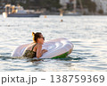 Woman wear green swimsuit relax inflatable ring calm sea near yachts forested coast sunset warm summer sunlight. Female person peaceful moment  leisure freedom vacation lifestyle serene getaway mood 138759369