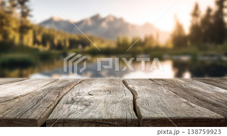 Rustic wooden tabletop with mountain lake landscape and sunrise light in the background 138759923