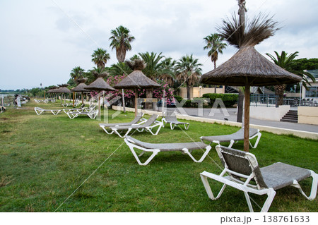 明け方の海岸沿いに並んだ茅葺屋根のパラソルとビーチベッド　地中海に浮かぶフランス領のコルシカ島にて 138761633