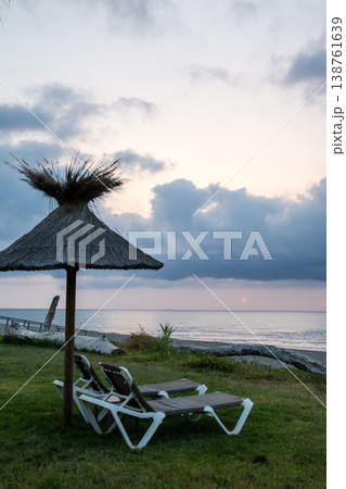 明け方の海岸沿いに並んだ茅葺屋根のパラソルとビーチベッド 地中海に浮かぶフランス領のコルシカ島にて 明け方の海岸沿いに並んだ茅葺屋根のパラソルとビーチベッド 地中海に浮かぶフランス領のコルシカ島にて 138761639