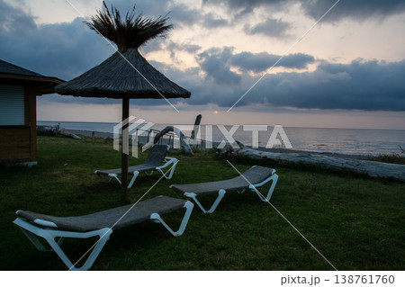明け方の海岸沿いに並んだ茅葺屋根のパラソルとビーチベッド　地中海に浮かぶフランス領のコルシカ島にて 138761760