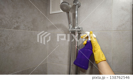 Person cleans shower with spray bottle and cloth in bathroom at home Person cleans shower with spray bottle and cloth in bathroom at home 138762546