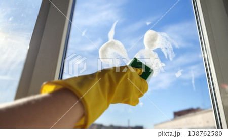 Cleaning a window with a sponge and soap on a clear sunny day Cleaning a window with a sponge and soap on a clear sunny day 138762580