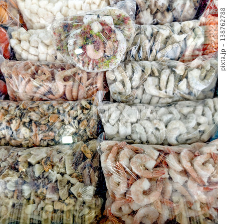 Assorted seafood packages displayed in clear plastic bags, including shrimp, fish, and other marine products, arranged neatly for sale at a market 138762788