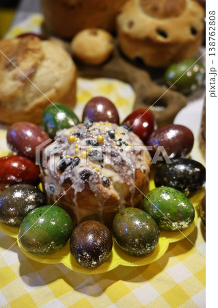 A festive arrangement of elaborately decorated Easter kulich cakes and dyed eggs presented on a yellow plate atop a patterned tablecloth A festive arrangement of elaborately decorated Easter kulich cakes and dyed eggs presented on a yellow plate atop a patterned tablecloth 138762808