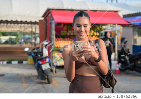 Smiling Thai Woman Using Smartphone at Tropical Market Outdoor Modern Digital Lifestyle Concept Smiling Thai Woman Using Smartphone at Tropical Market Outdoor Modern Digital Lifestyle Concept 138762866