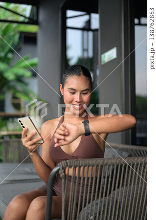 Young Thai Woman Syncing Fitness Data After Workout Gym Training Done Concept Young Thai Woman Syncing Fitness Data After Workout Gym Training Done Concept 138762883