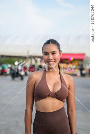 Smiling Young Thai Fitness Influencer in Brown Activewear at Outdoor Market Healthy Lifestyle Concept 138763044