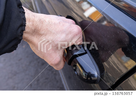 With determination, a man reaches for the handle of a stylish black car, excitement evident as he prepares to embark on his journey With determination, a man reaches for the handle of a stylish black car, excitement evident as he prepares to embark on his journey 138763057