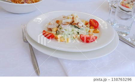 Crisp romaine lettuce topped with grilled chicken, golden croutons, shaved parmesan, halved cherry tomatoes on pristine white ceramic plate Crisp romaine lettuce topped with grilled chicken, golden croutons, shaved parmesan, halved cherry tomatoes on pristine white ceramic plate 138763296