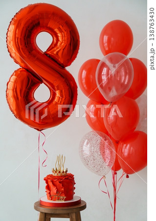 Metallic orange number eight balloon with red cake and confetti balloons on wooden stool for birthday celebration 138763430