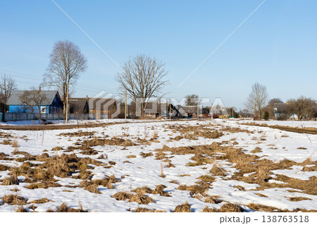 Frozen terrain opening to muddy patches and scattered dwellings beneath blue sky Frozen terrain opening to muddy patches and scattered dwellings beneath blue sky 138763518