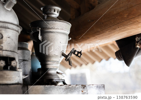Old metal scene. Vintage metal tap hidden beneath sunlit wooden shelter with aging patina 138763590