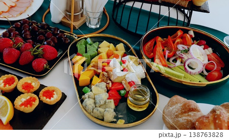 Beautifully arranged catering table featuring a diverse selection of appetizers, including cheeses, fresh vegetables, colorful fruits, and delicate canapes Beautifully arranged catering table featuring a diverse selection of appetizers, including cheeses, fresh vegetables, colorful fruits, and delicate canapes 138763828