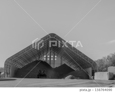 Large storage facility holds various materials in a covered structure in an industrial area during daytime Large storage facility holds various materials in a covered structure in an industrial area during daytime 138764090