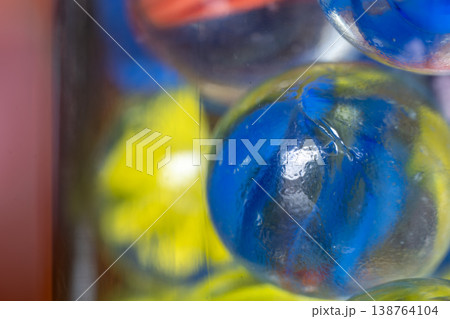 Macro closeup photo of a glass jar full of cat's eye marbles. 138764104