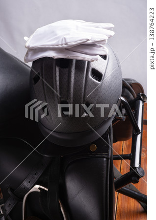 Black professional leather dressage saddle in complete with riding helmet and gloves. close up Black professional leather dressage saddle in complete with riding helmet and gloves. close up 138764223