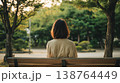 公園のベンチに座り緑を眺める女性の後ろ姿 138764449