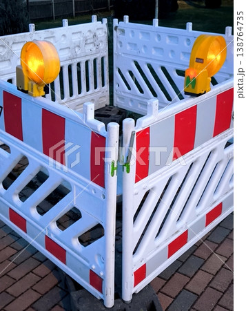 Plastic safety barriers with flashing yellow lights are installed in the pedestrian area.  138764735