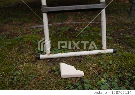 White broken foam piece on grass below a metal ladder frame outdoors White broken foam piece on grass below a metal ladder frame outdoors 138765134