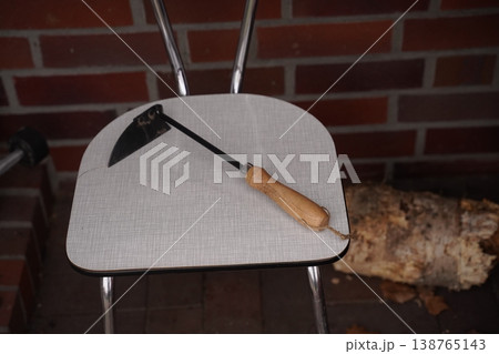 Metal fire tool with wooden handle on chair seat near brick fireplace Metal fire tool with wooden handle on chair seat near brick fireplace 138765143