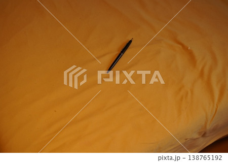 Black pen lying on wrinkled fabric surface in warm light 138765192
