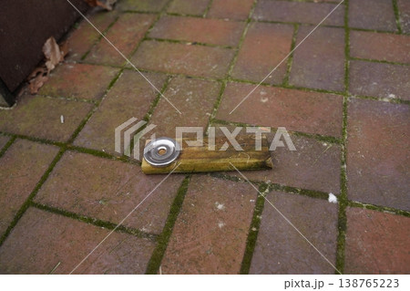 Wooden plank with a metal can lid on brick paving, outdoors near a wall Wooden plank with a metal can lid on brick paving, outdoors near a wall 138765223