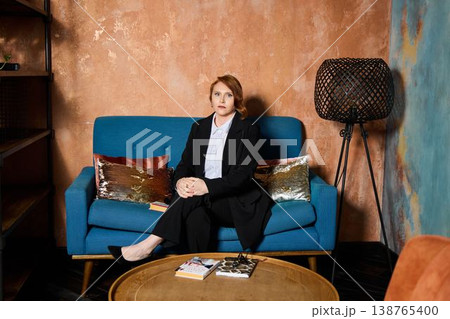 Professional woman seated comfortably with coffee and writing tools Professional woman seated comfortably with coffee and writing tools 138765400