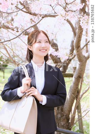 桜の下で微笑む新入社員のリクルートスーツ姿の若い女性・春の入社式イメージ 138765682