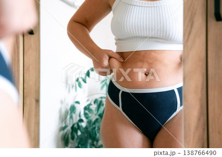 Woman overweight body. Female touching stomach near mirror. Weig Woman overweight body. Female touching stomach near mirror. Weig 138766490