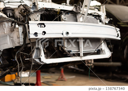 Close up of car front chassis and radiator exposed during repair in workshop mechanical service maintenance automotive parts and tools industrial environment 138767340
