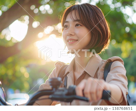 木漏れ日の中、自転車で通勤する笑顔の若い女性 138768651