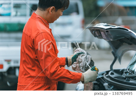 エンジンオイルのレベルゲージを確認する自動車整備士 138769495