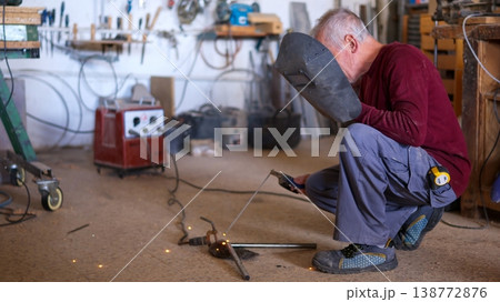 Senior craftsman welding metal in a workshop 138772876